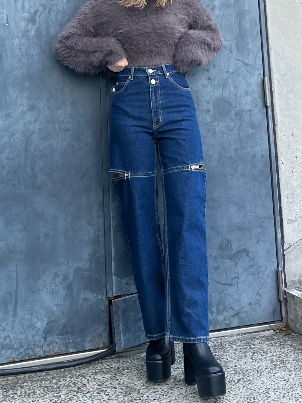 グレー系のニット/セーター、ブルー系のデニムパンツ、ブラック系のブーツを着用したレディースの秋コーディネートの5枚目の写真