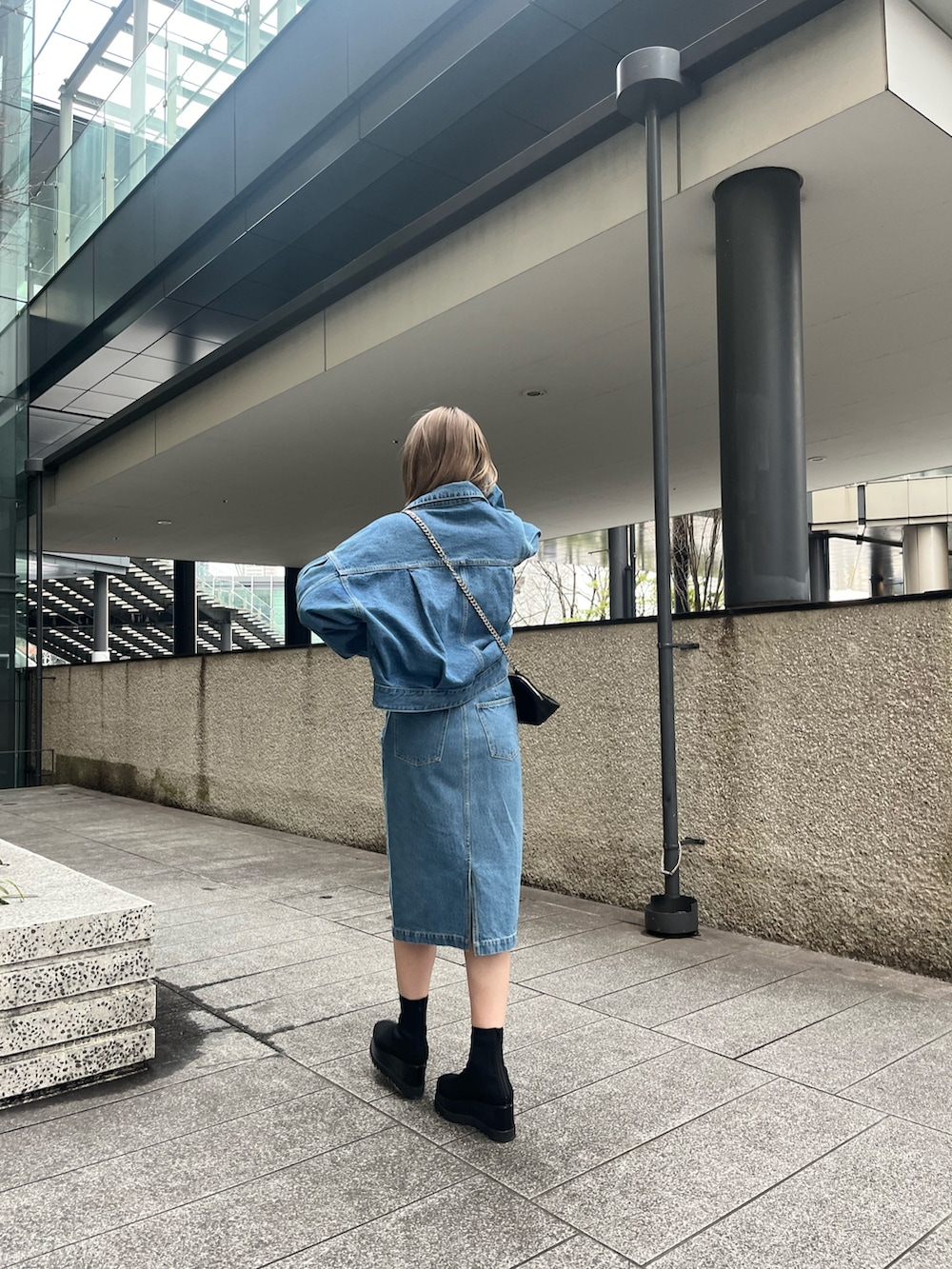 ブルー系のデニムジャケット、ブルー系のワンピース、ブラック系のブーツを着用したレディースの冬コーディネートの3枚目の写真