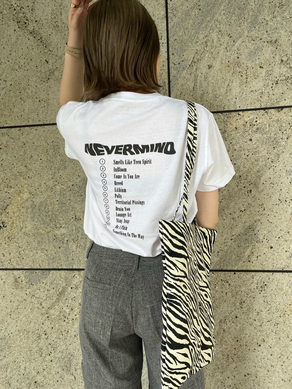 ホワイト系のTシャツ/カットソー、グレー系のスラックス、その他のトートバッグを着用したレディースの夏コーディネートの4枚目の写真