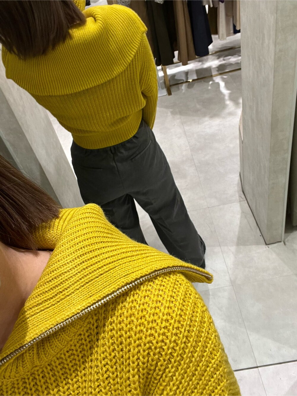 イエロー系のニット/セーター、ブラック系のブーツ、グレー系のスラックスを着用したレディースの秋コーディネートの4枚目の写真