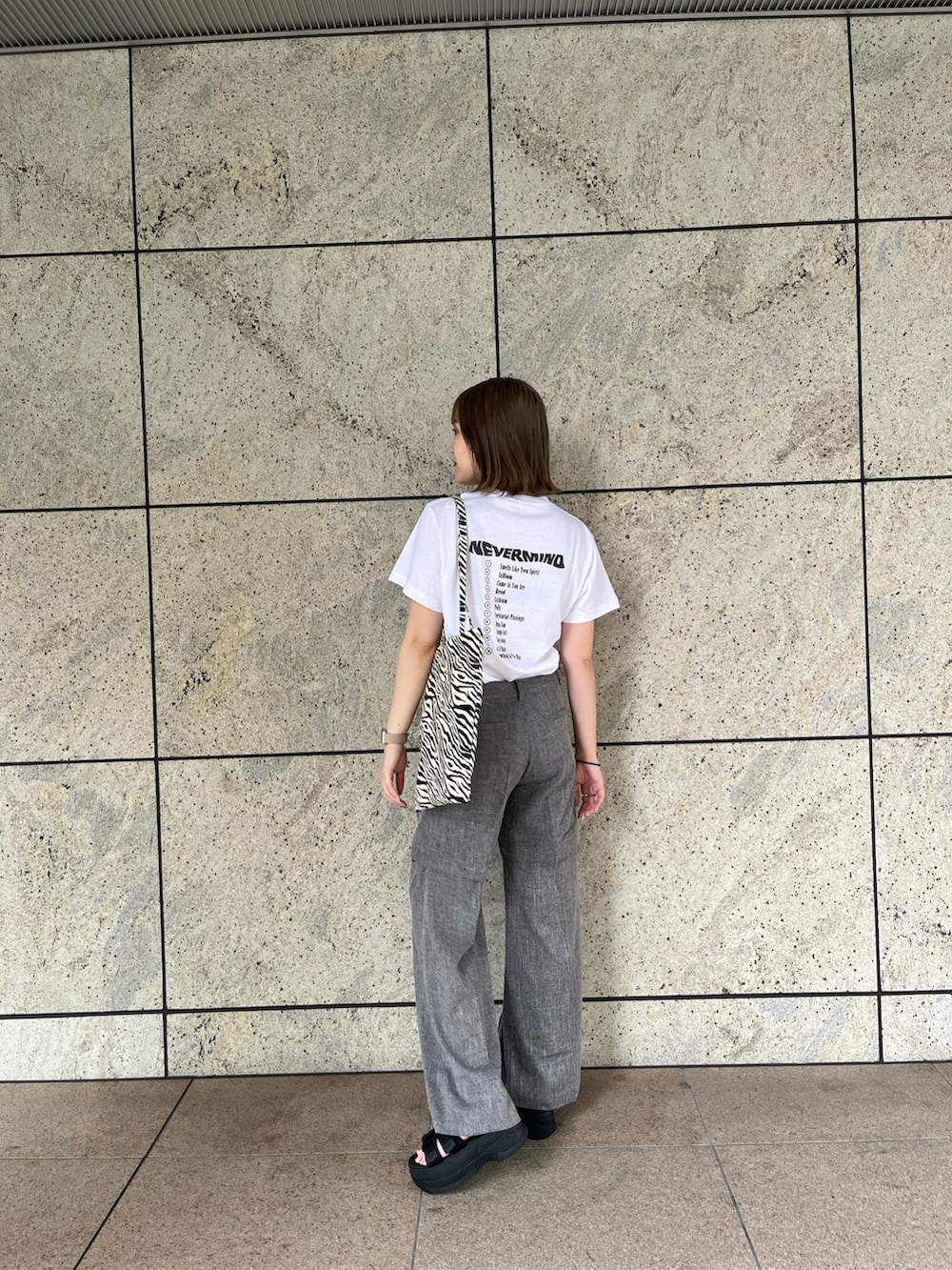 ホワイト系のTシャツ/カットソー、グレー系のスラックス、その他のトートバッグを着用したレディースの夏コーディネートの2枚目の写真