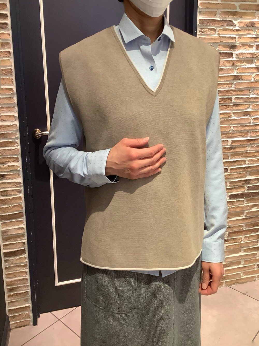 ベージュ系のニット/セーター、ブルー系のビジネスシャツを着用したレディースの冬コーディネートの2枚目の写真