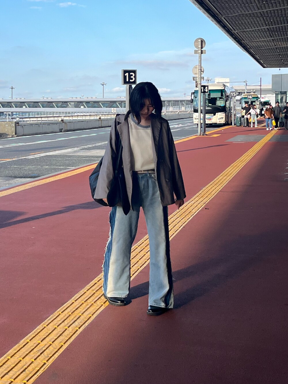 ブルー系のデニムパンツ、ホワイト系のニット/セーター、ブラック系のトートバッグを着用したレディースの夏コーディネートの3枚目の写真