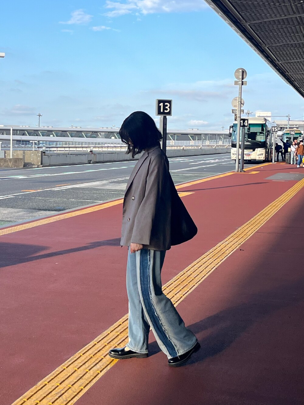 ブルー系のデニムパンツ、ホワイト系のニット/セーター、ブラック系のトートバッグを着用したレディースの夏コーディネートの2枚目の写真