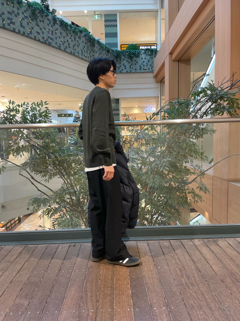 グリーン系のニット/セーター、ブラック系のその他パンツ、ブラック系のダウンジャケット/コートを着用したメンズの秋コーディネートの3枚目の写真