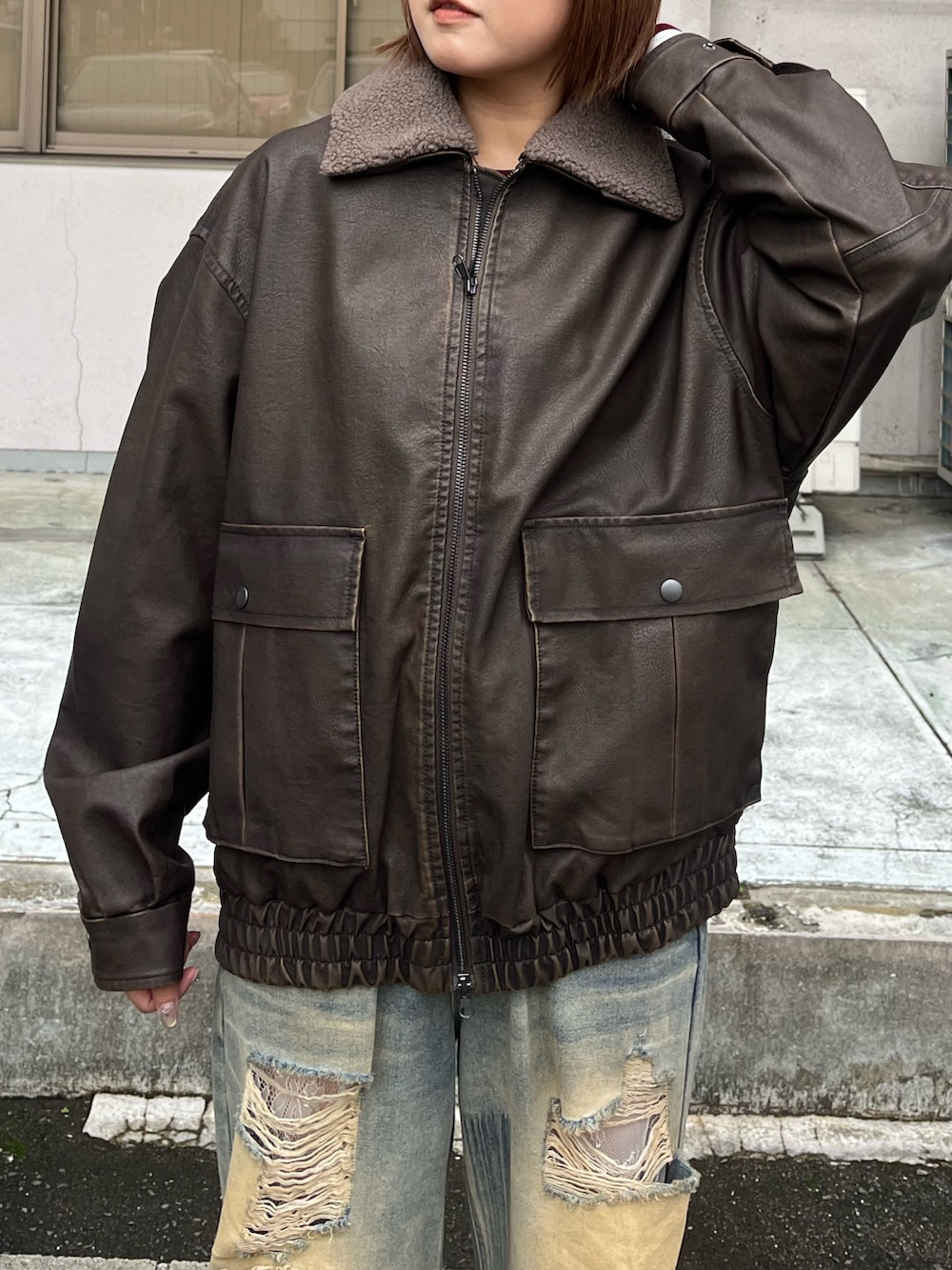 ブラウン系のブルゾン、ブルー系のデニムパンツを着用したレディースの秋コーディネートの2枚目の写真