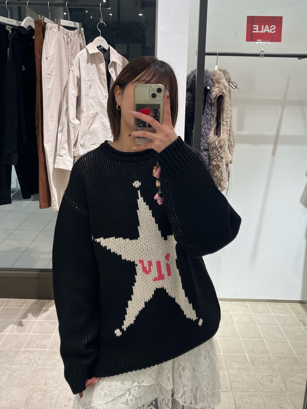 ブラック系のニット/セーター、ホワイト系のスカート、ブルー系のデニムパンツを着用したレディースの冬コーディネートの2枚目の写真