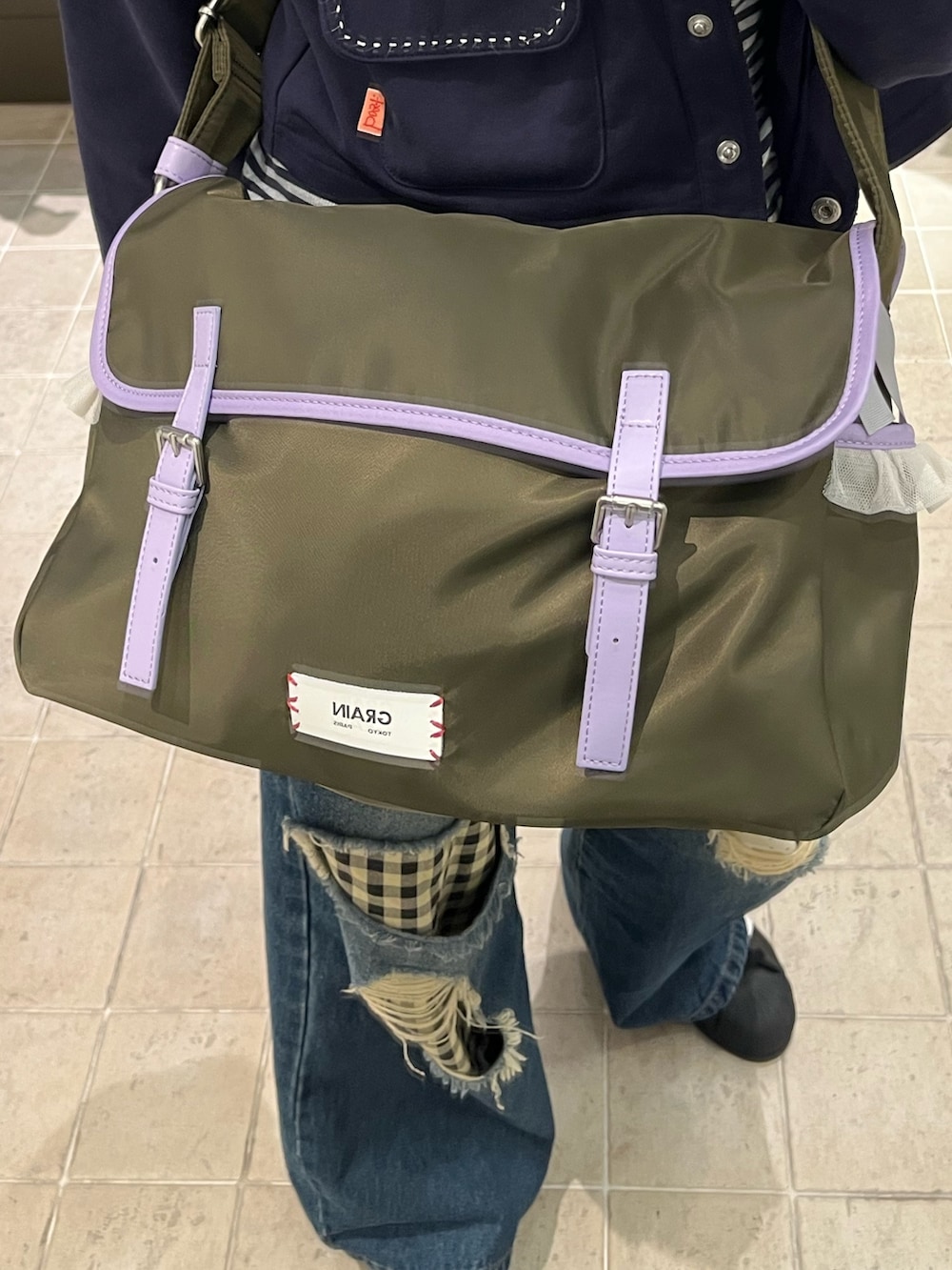 グリーン系のショルダーバッグを着用したレディースの冬コーディネートの2枚目の写真