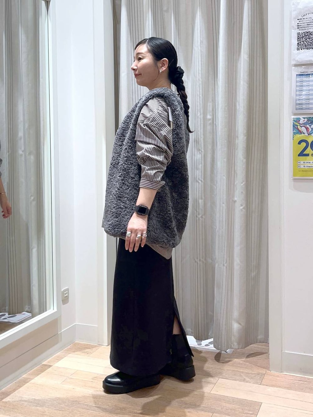 グレー系のベスト、ブラック系のスカート、ブラック系のブーツを着用したレディースの秋コーディネートの2枚目の写真