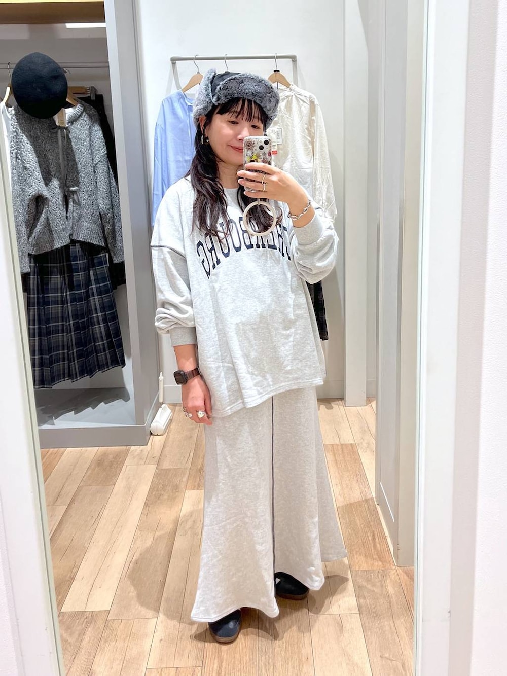 グレー系のスウェット、グレー系のスカート、ブラック系のキャップを着用したレディースの秋コーディネートの2枚目の写真
