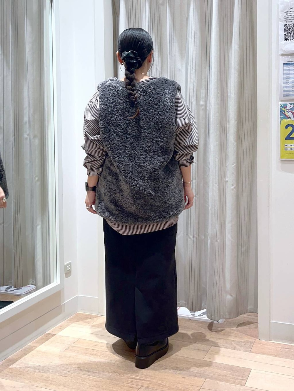 グレー系のベスト、ブラック系のスカート、ブラック系のブーツを着用したレディースの秋コーディネートの3枚目の写真