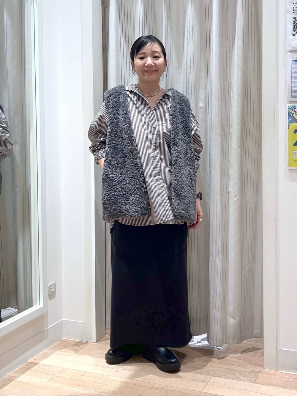 グレー系のベスト、ブラック系のスカート、ブラック系のブーツを着用したレディースの秋コーディネートの6枚目の写真