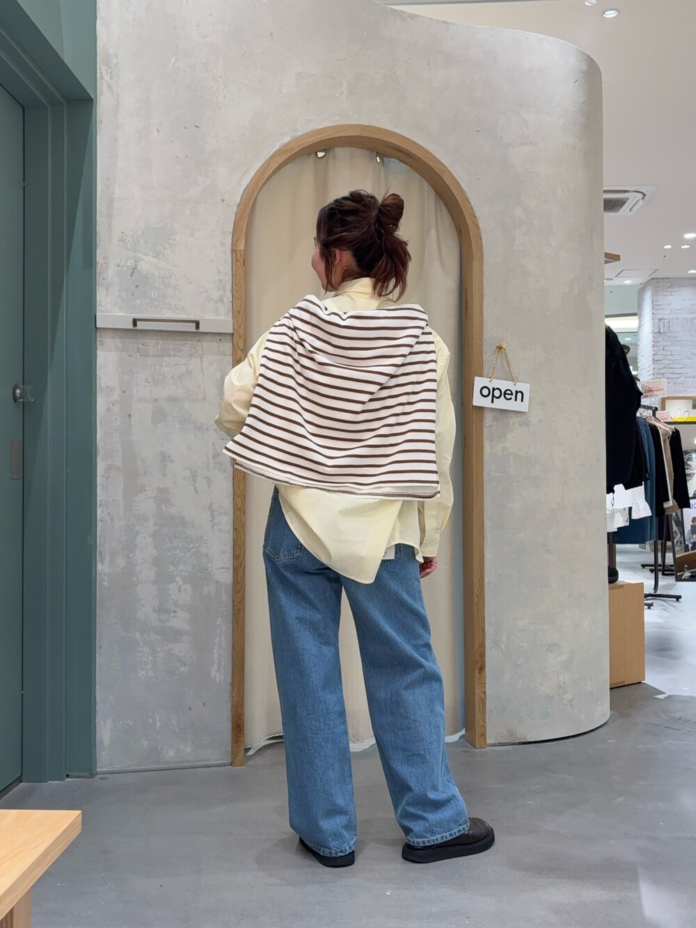 イエロー系のシャツ/ブラウス、ブラウン系のTシャツ/カットソー、ブルー系のデニムパンツを着用したレディースの春コーディネートの3枚目の写真