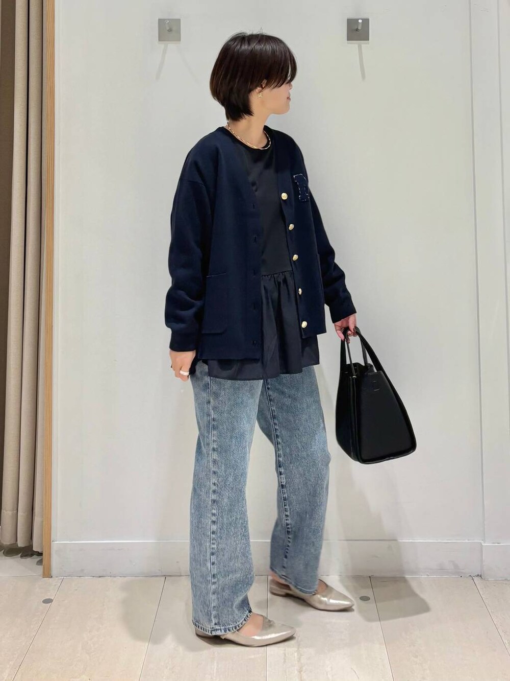 ブルー系のデニムパンツ、ブルー系のカーディガン/ボレロ、ブラック系のトートバッグを着用したレディースの秋コーディネートの4枚目の写真