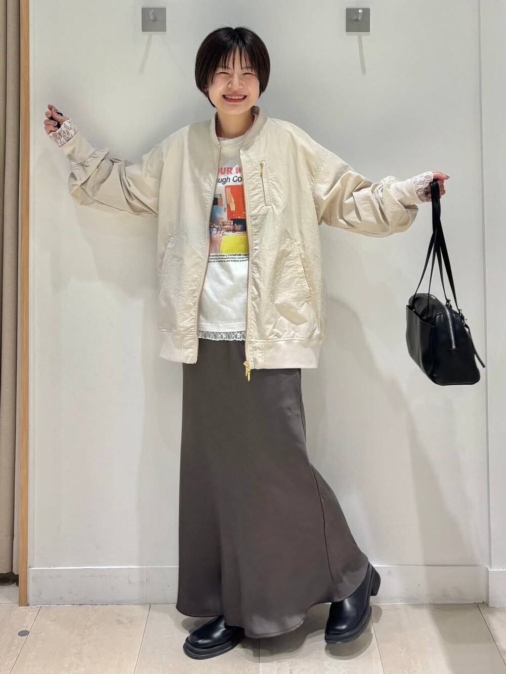 ホワイト系のTシャツ/カットソー、ベージュ系のブルゾン、ブラウン系のスカートを着用したレディースの春コーディネートの6枚目の写真