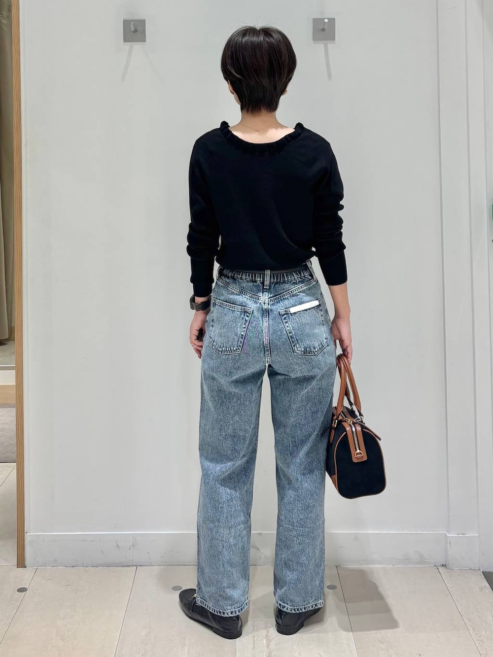 ブラック系のローファー、ブルー系のデニムパンツ、ブラック系のニット/セーターを着用したレディースの秋コーディネートの4枚目の写真