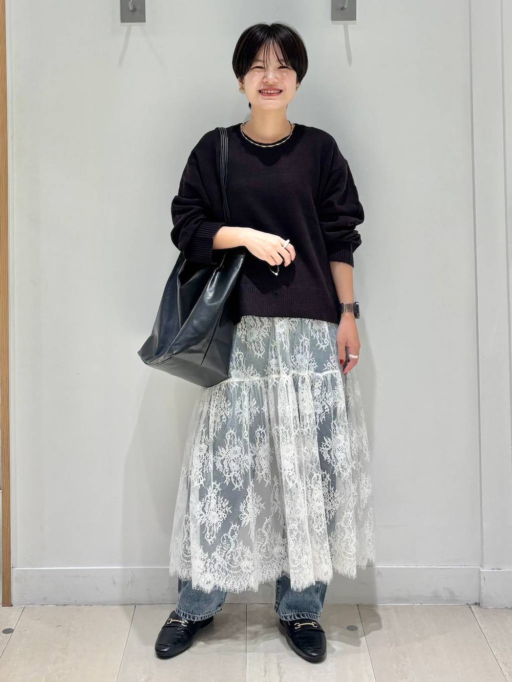 ブラック系のローファー、ブルー系のデニムパンツ、ブラウン系のワンピースを着用したレディースの秋コーディネートの5枚目の写真