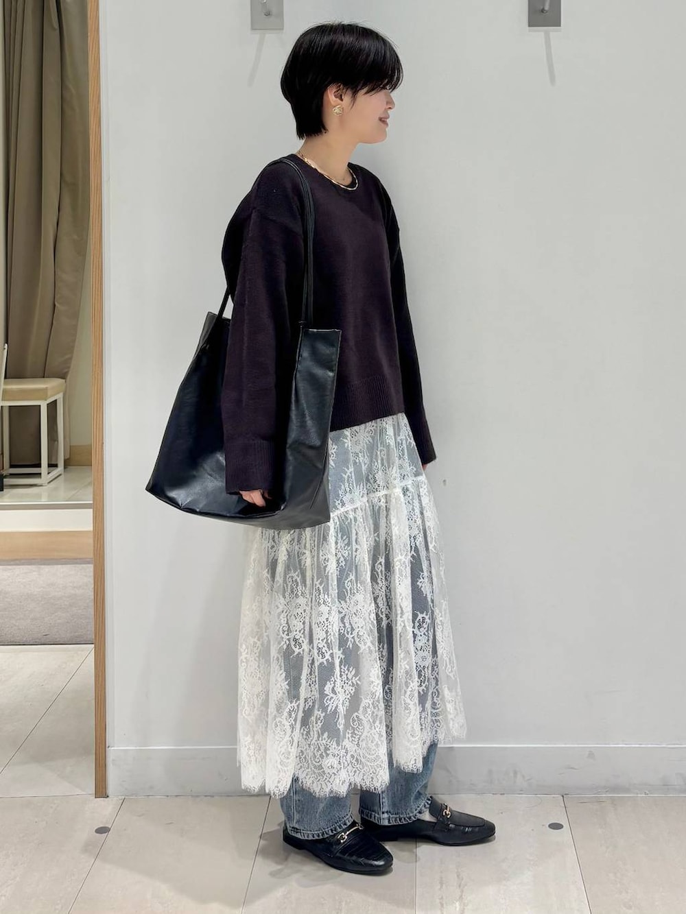 ブラック系のローファー、ブルー系のデニムパンツ、ブラウン系のワンピースを着用したレディースの秋コーディネートの4枚目の写真