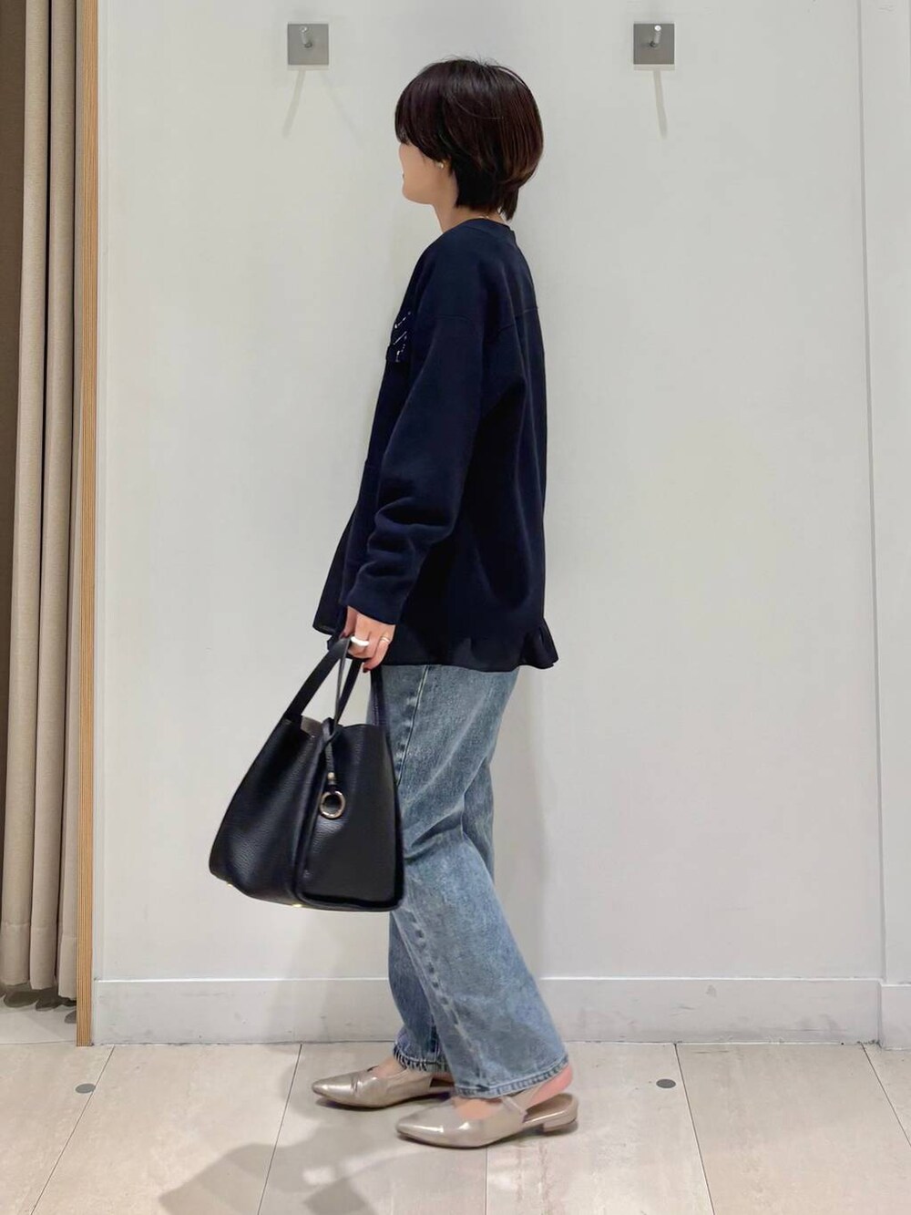 ブルー系のデニムパンツ、ブルー系のカーディガン/ボレロ、ブラック系のトートバッグを着用したレディースの秋コーディネートの2枚目の写真