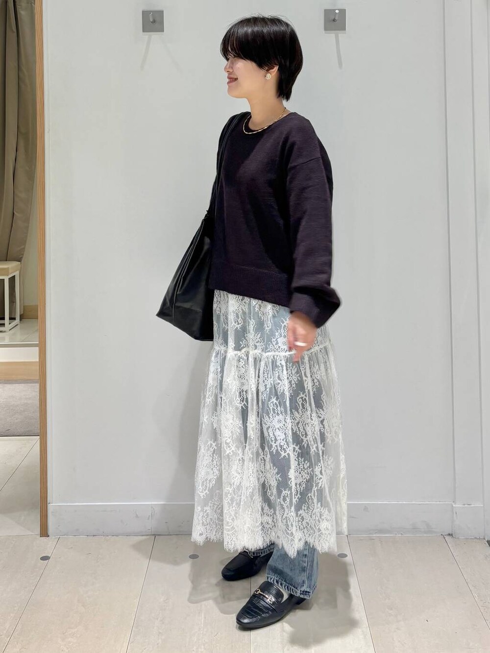 ブラック系のローファー、ブルー系のデニムパンツ、ブラウン系のワンピースを着用したレディースの秋コーディネートの2枚目の写真