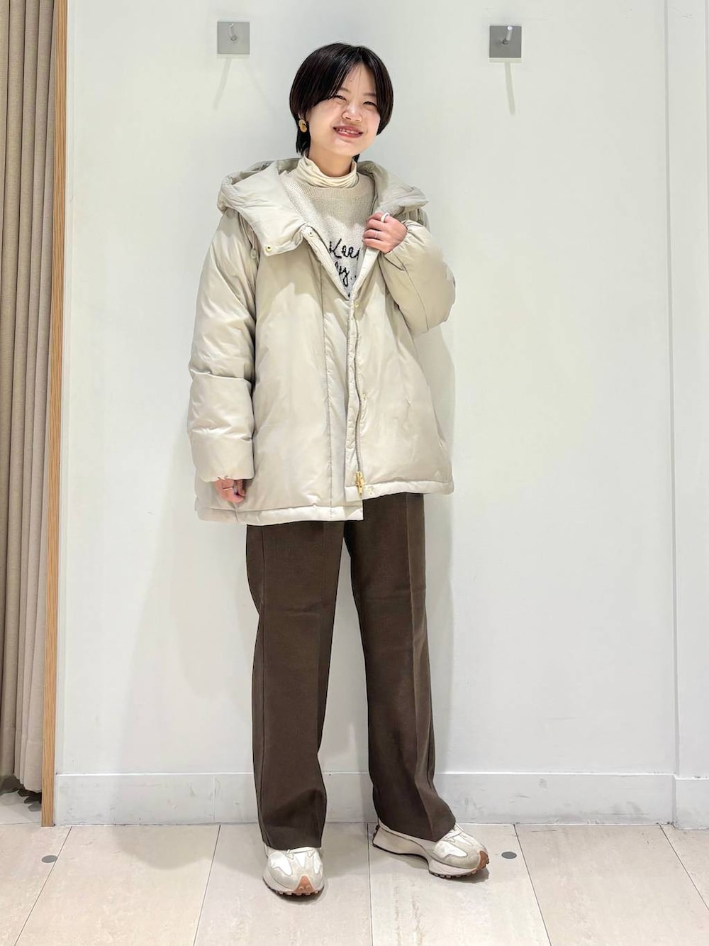 ベージュ系のダウンジャケット/コート、ブラウン系のその他パンツ、ホワイト系のTシャツ/カットソーを着用したレディースの冬コーディネートの4枚目の写真