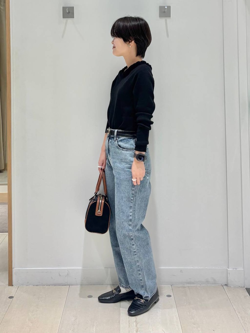 ブラック系のローファー、ブルー系のデニムパンツ、ブラック系のニット/セーターを着用したレディースの秋コーディネートの3枚目の写真