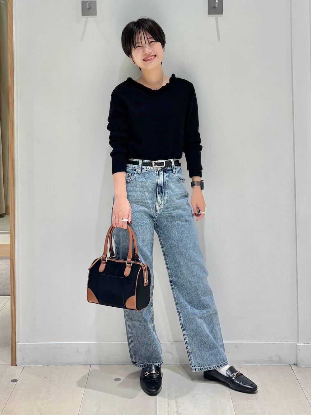 ブラック系のローファー、ブルー系のデニムパンツ、ブラック系のニット/セーターを着用したレディースの秋コーディネートの6枚目の写真