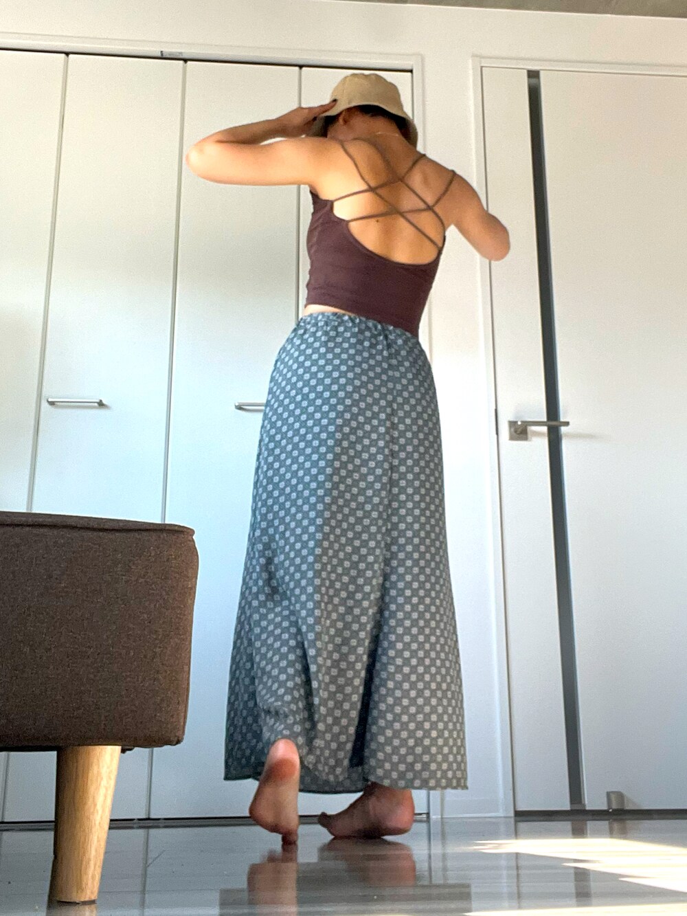 ブラウン系のキャミソール、ブルー系のスカート、ベージュ系の帽子を着用したレディースの夏コーディネートの2枚目の写真