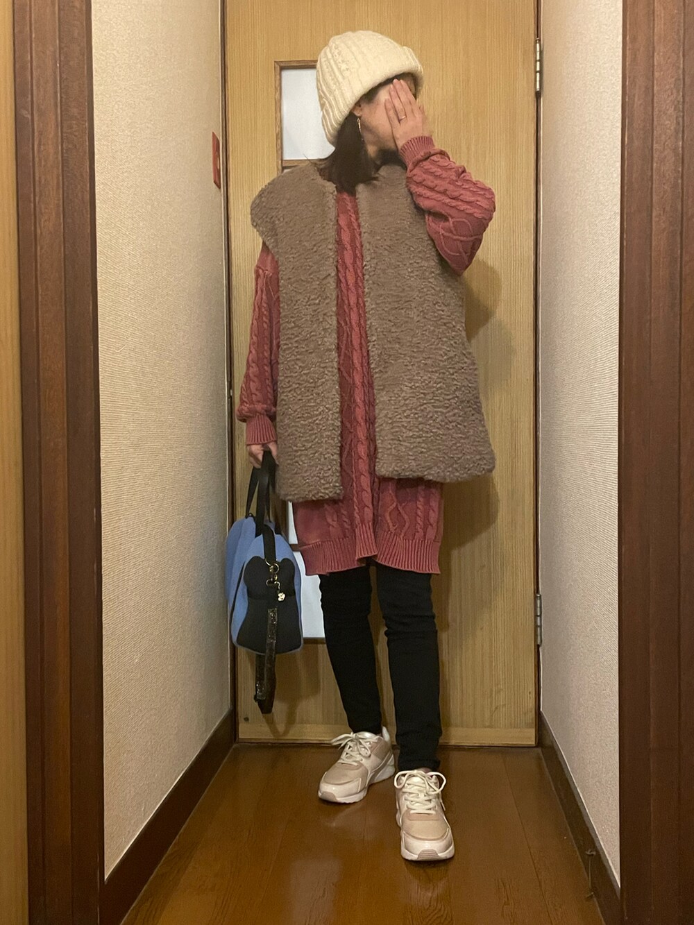 ピンク系のニット/セーター、ブラック系のパンツ、ベージュ系のスニーカーを着用したレディースの春コーディネートの2枚目の写真