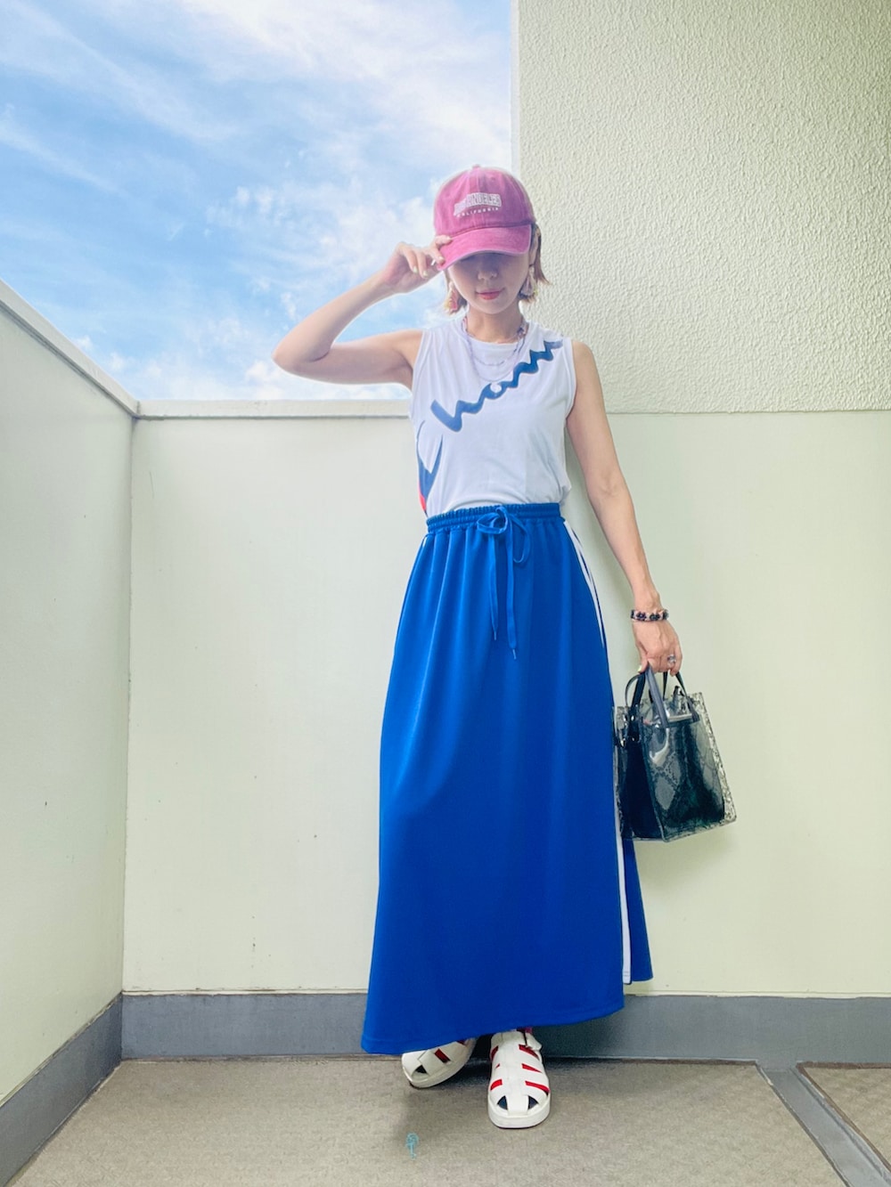 ブルー系のスカート、ホワイト系のサンダル、ブラウン系のシャツ/ブラウスを着用したレディースの夏コーディネートの2枚目の写真