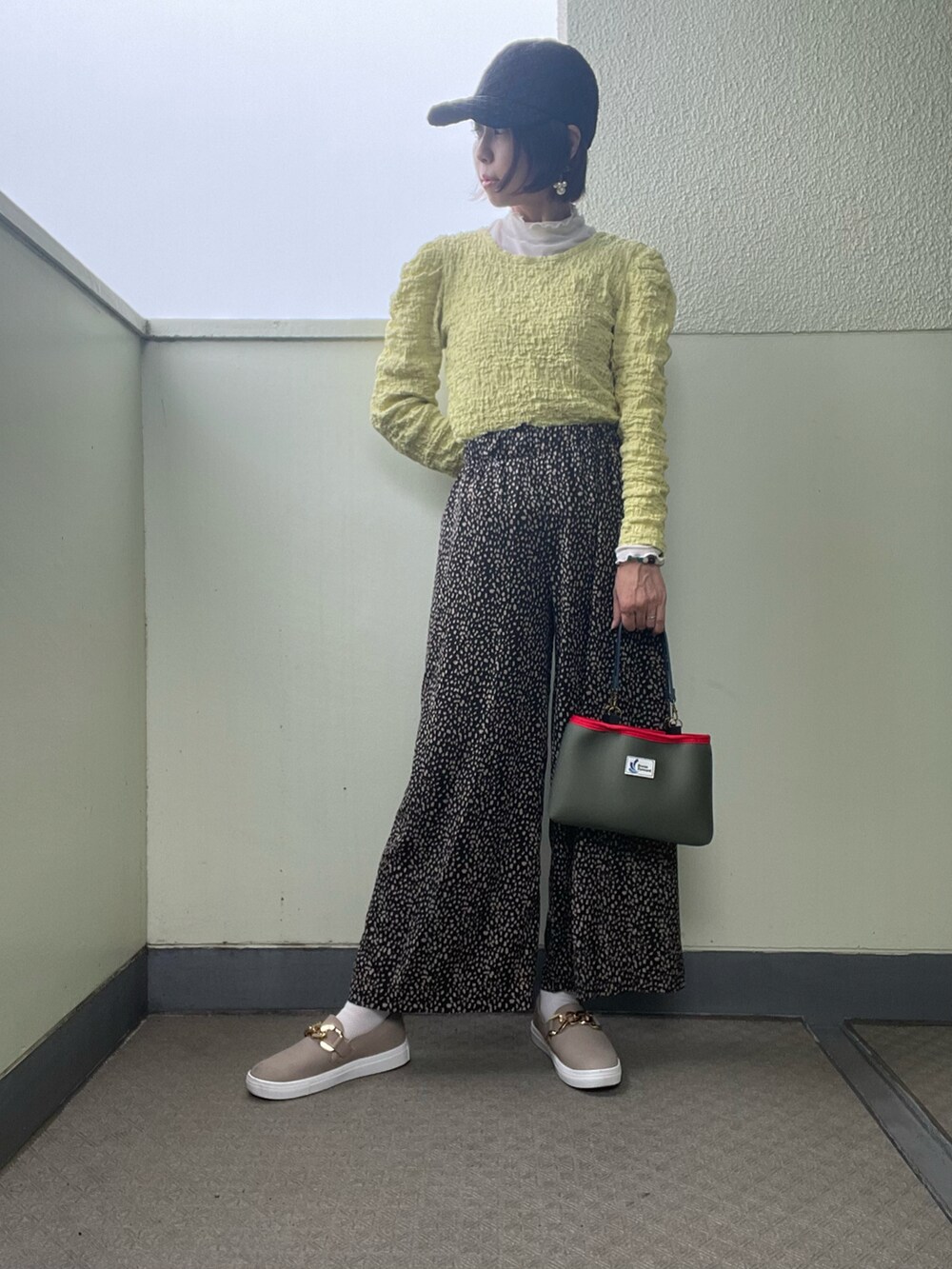 ブラック系のその他パンツ、その他のスニーカー、ベージュ系のベストを着用したレディースの春コーディネートの2枚目の写真