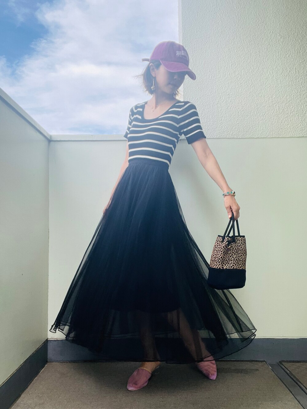 ブラック系のワンピース、ブラック系のバッグ、パープル系のサンダルを着用したレディースの夏コーディネートの3枚目の写真