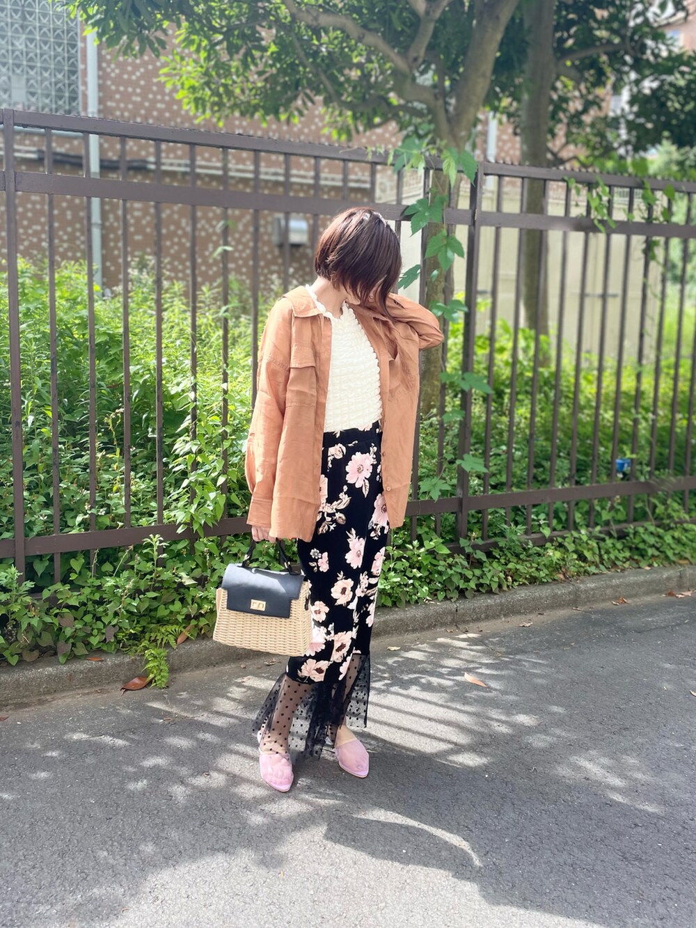 ベージュ系のバッグ、ブラック系のスカート、ホワイト系のTシャツ/カットソーを着用したレディースの夏コーディネートの2枚目の写真