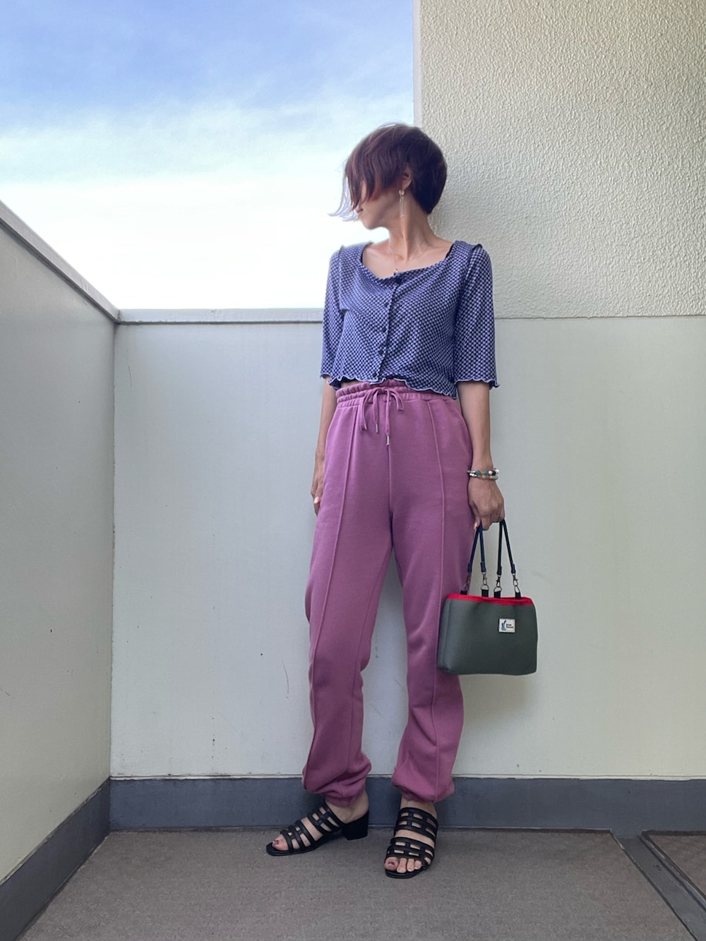 ピンク系のスウェットパンツ、グリーン系のバッグ、ブラック系のサンダルを着用したレディースの秋コーディネートの2枚目の写真