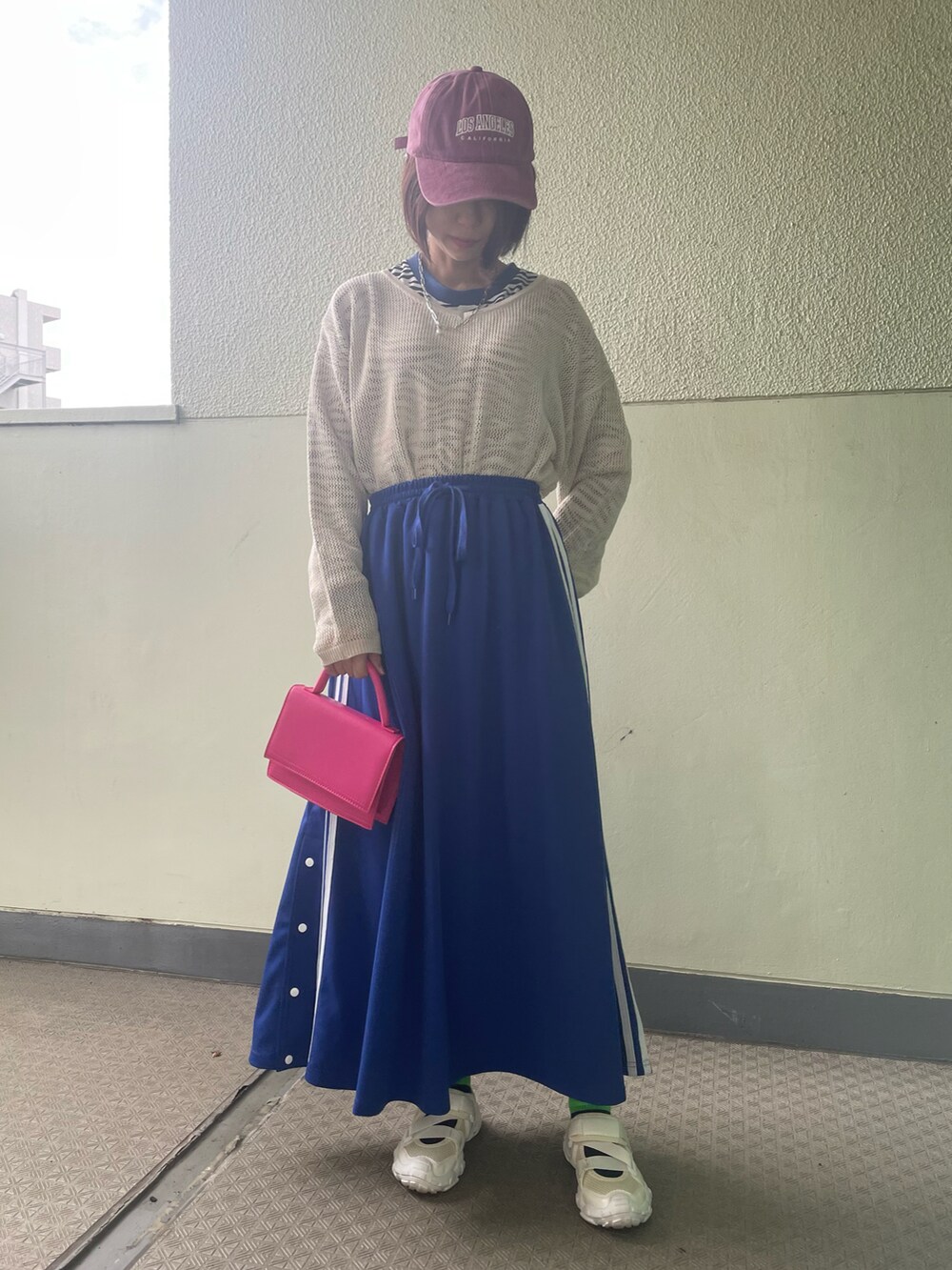 ブルー系のスカート、ホワイト系のシューズ、ピンク系のバッグを着用したレディースの春コーディネートの2枚目の写真