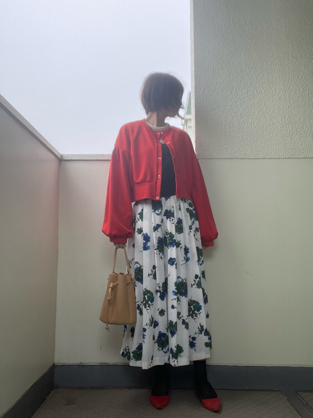 レッド系のパンプス、ホワイト系のスカート、ブラック系のバッグを着用したレディースの春コーディネートの2枚目の写真