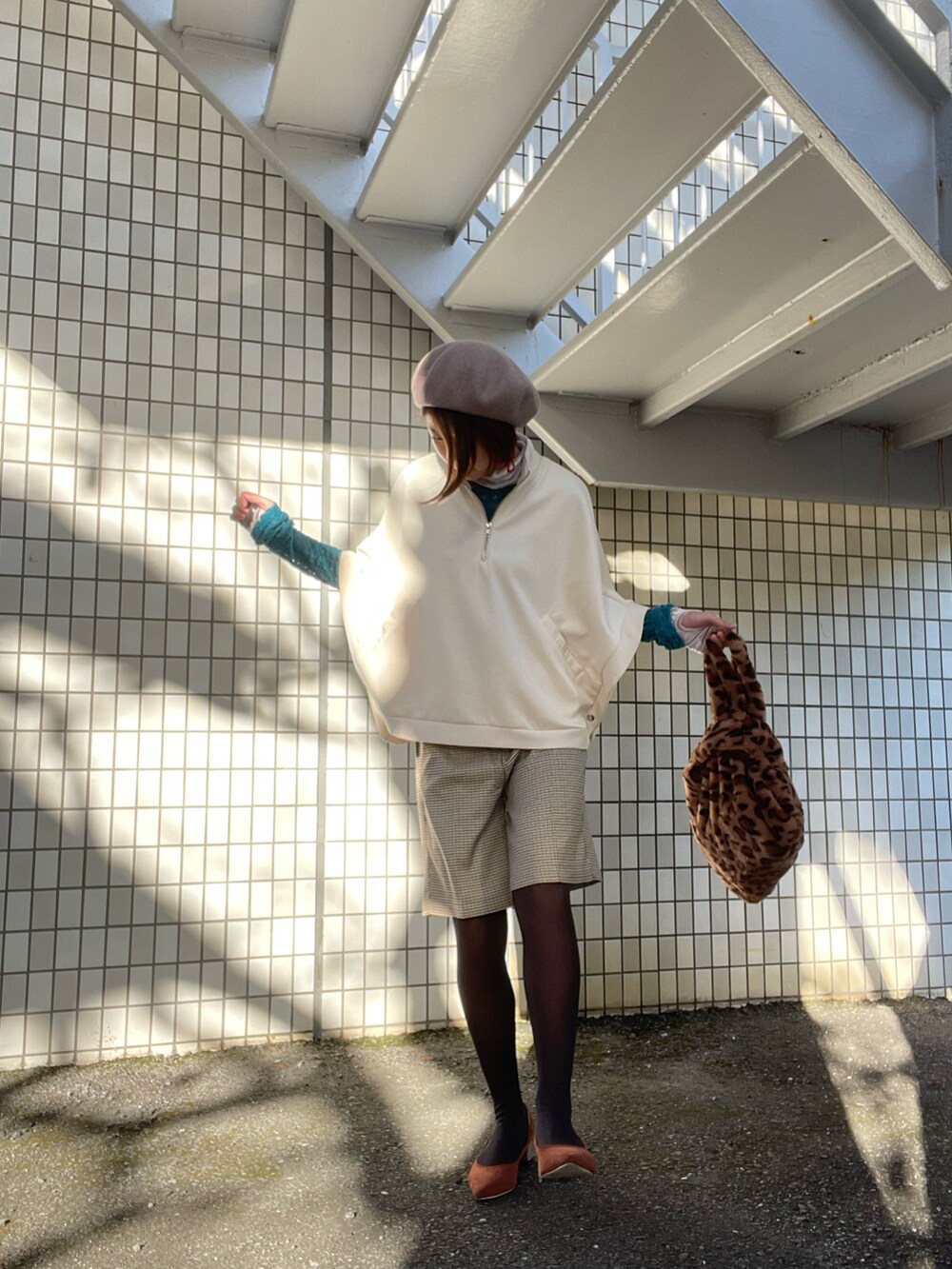 ブラウン系のパンプス、ブラウン系のバッグ、ホワイト系のトップスを着用したレディースの秋コーディネートの2枚目の写真