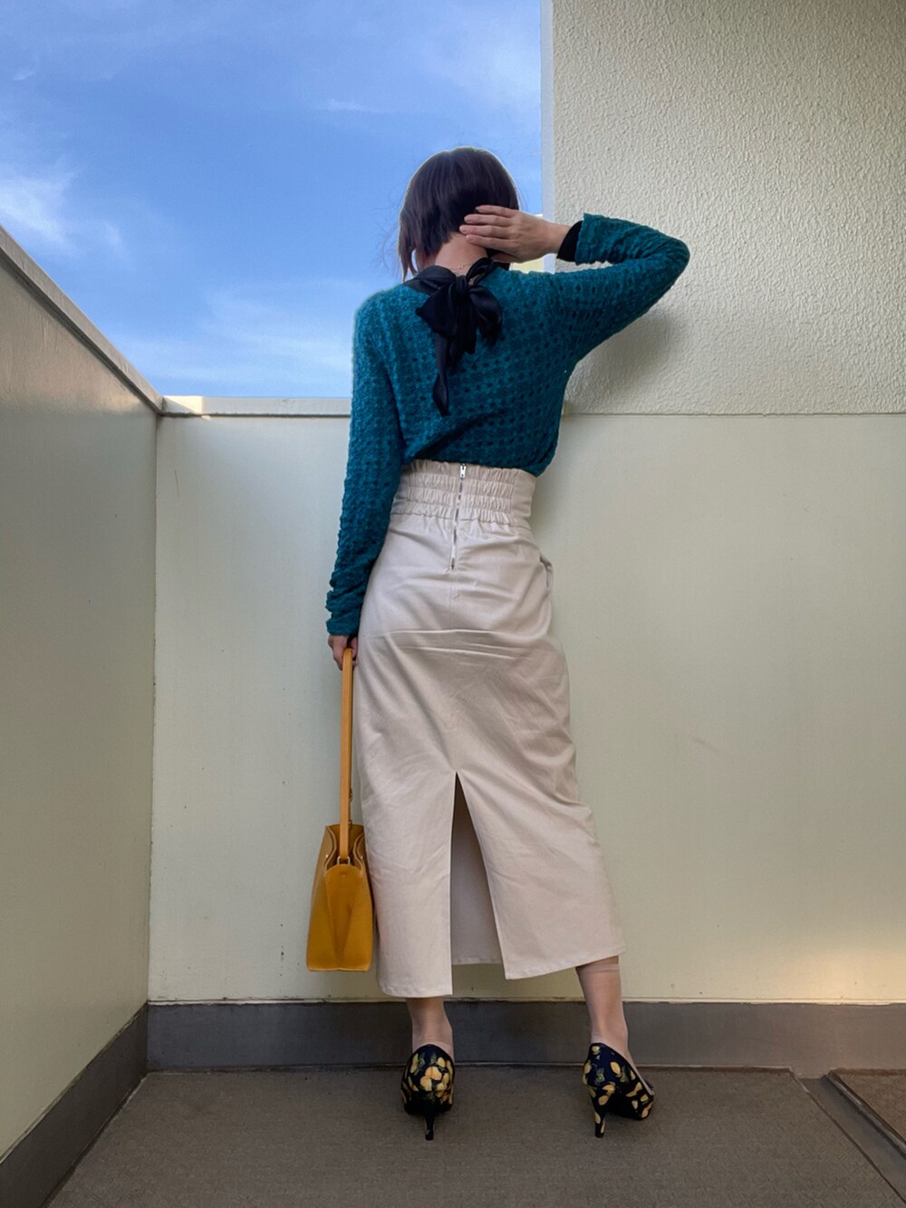 イエロー系のバッグ、ブルー系のシューズ、ブラック系のスカートを着用したレディースの春コーディネートの3枚目の写真