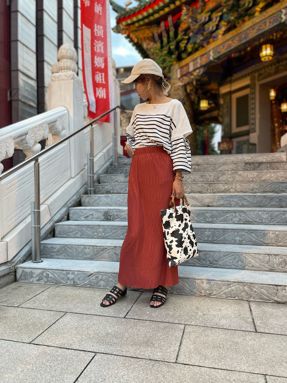 ブラック系のサンダル、オレンジ系のスカート、ブラック系のTシャツ/カットソーを着用したレディースの夏コーディネートの2枚目の写真