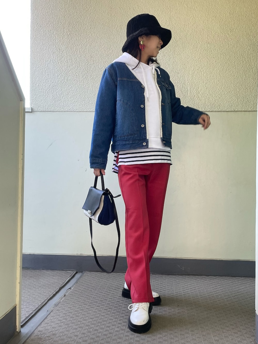 ホワイト系のシューズ、レッド系のパンツ、ブルー系のデニムジャケットを着用したレディースの冬コーディネートの2枚目の写真