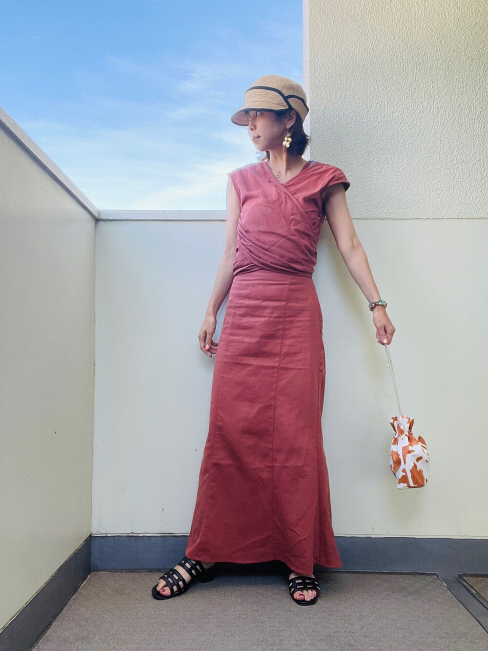 ホワイト系のショルダーバッグ、ブラック系のサンダル、オレンジ系のスカートを着用したレディースの夏コーディネートの2枚目の写真