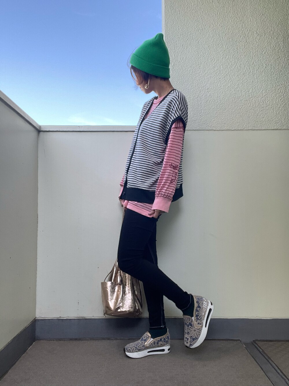 ブラック系のデニムパンツ、ゴールド系のシューズ、ゴールド系のトートバッグを着用したレディースの秋コーディネートの2枚目の写真