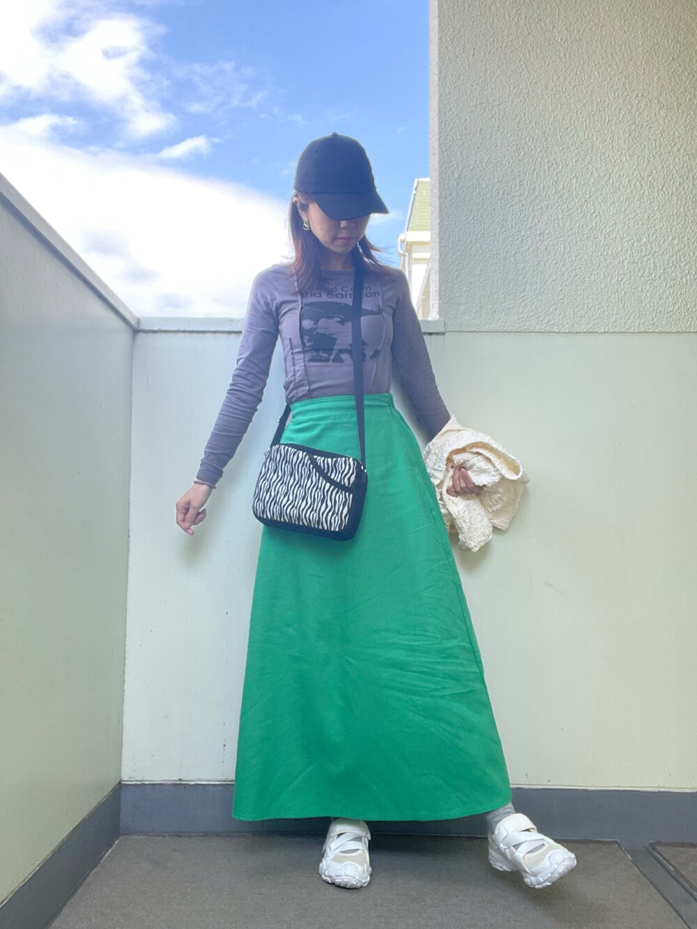 ホワイト系のシューズ、グリーン系のスカート、ホワイト系のショルダーバッグを着用したレディースの春コーディネートの2枚目の写真