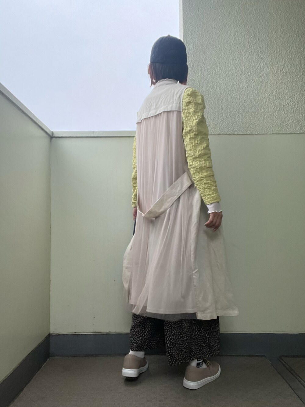ブラック系のその他パンツ、その他のスニーカー、ベージュ系のベストを着用したレディースの春コーディネートの3枚目の写真