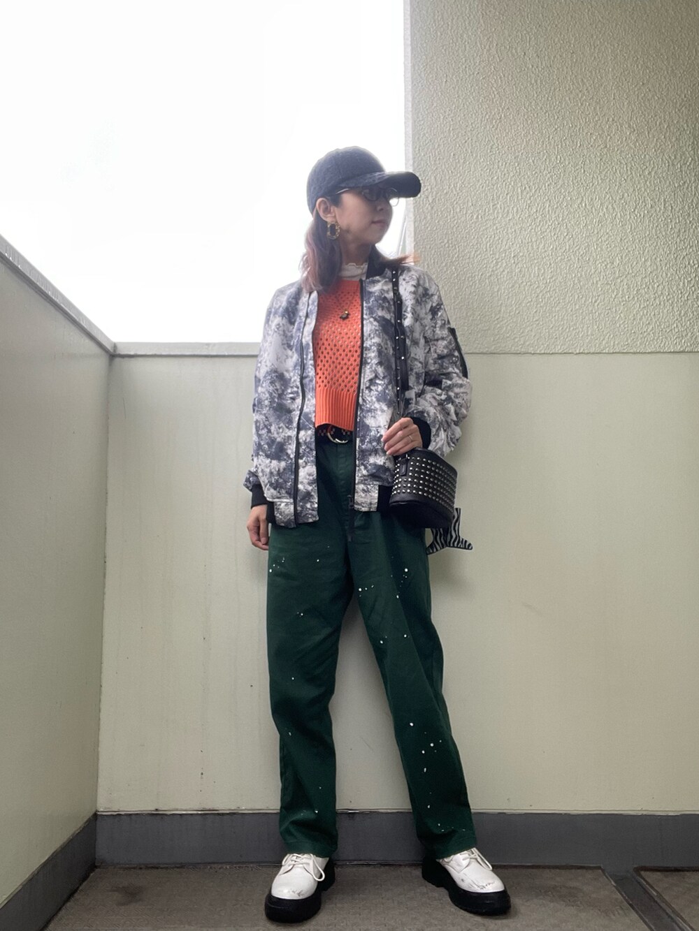 ホワイト系のシューズ、グリーン系のチノパンツ、オレンジ系のニット/セーターを着用したレディースの春コーディネートの2枚目の写真