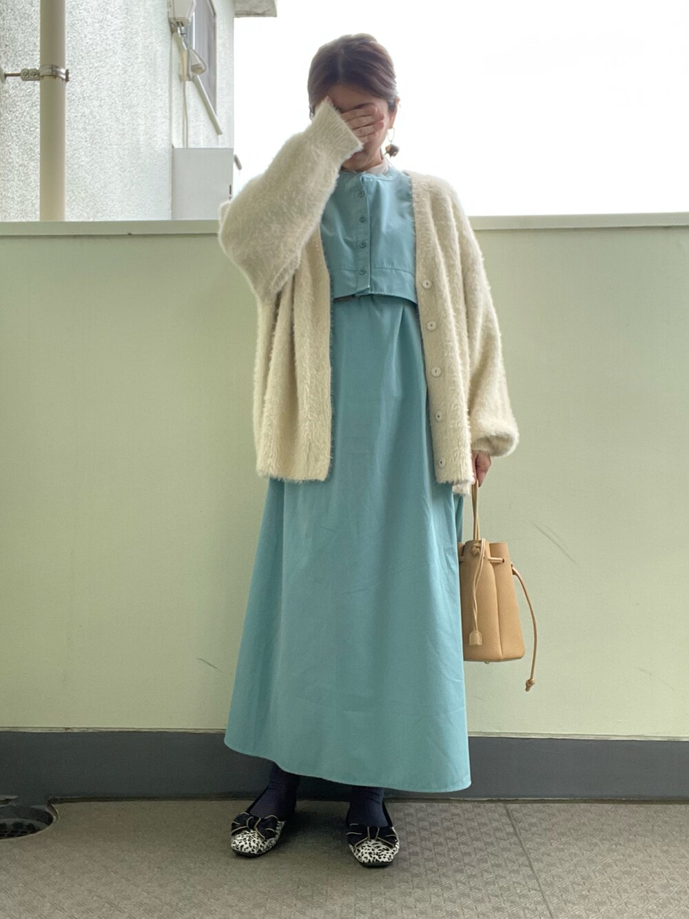 ブルー系のワンピース、ブラック系のバッグ、ホワイト系のカーディガン/ボレロを着用したレディースの春コーディネートの3枚目の写真