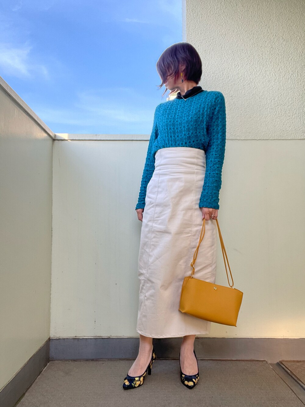 イエロー系のバッグ、ブルー系のシューズ、ブラック系のスカートを着用したレディースの春コーディネートの2枚目の写真