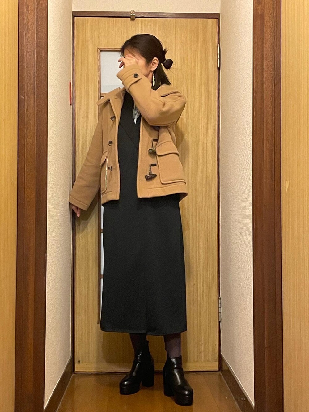 ブラック系のブーツ、ブラック系のベスト、ホワイト系のワンピースを着用したレディースの冬コーディネートの2枚目の写真