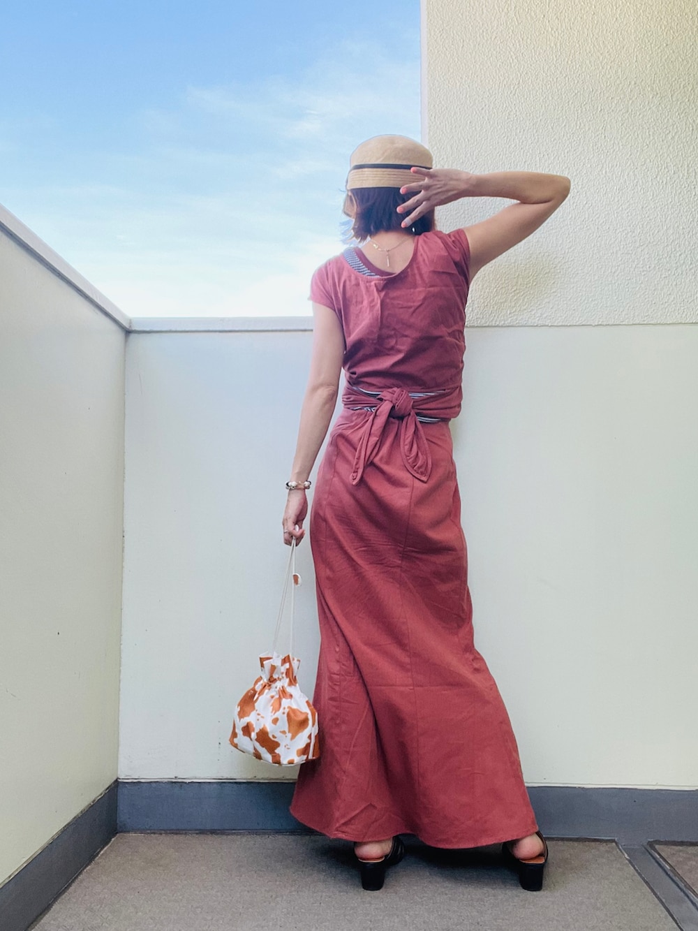 ホワイト系のショルダーバッグ、ブラック系のサンダル、オレンジ系のスカートを着用したレディースの夏コーディネートの3枚目の写真