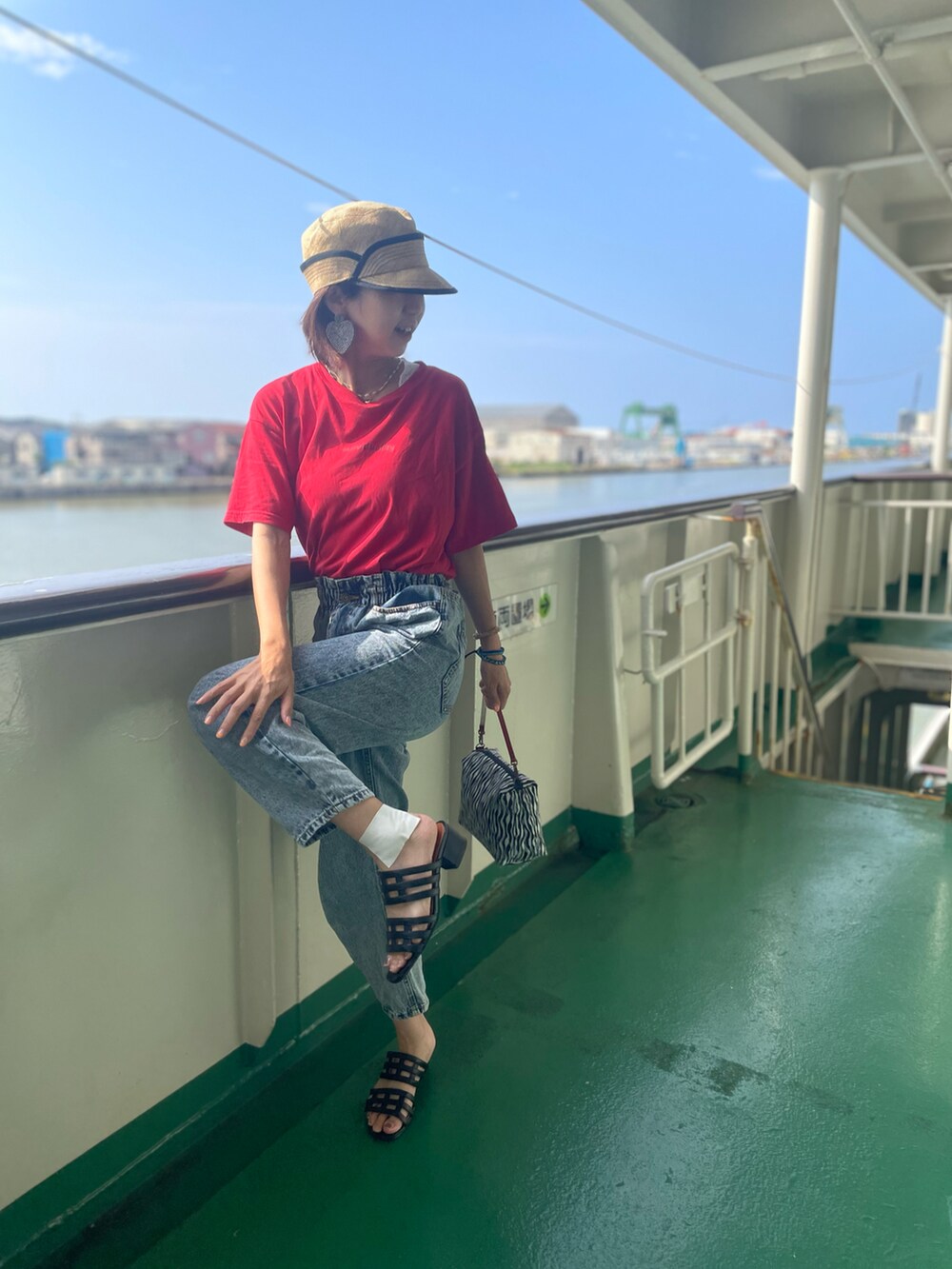 ブラック系のサンダル、ブルー系のデニムパンツ、レッド系のTシャツ/カットソーを着用したレディースの夏コーディネートの2枚目の写真